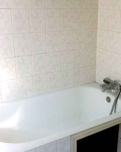 Ancienne baignoire dans une salle de bain carrelée de blanc