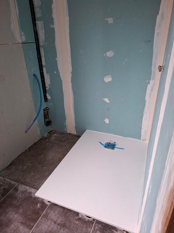 Salle d'eau en cours : receveur posé, murs en panneaux hydrofuges