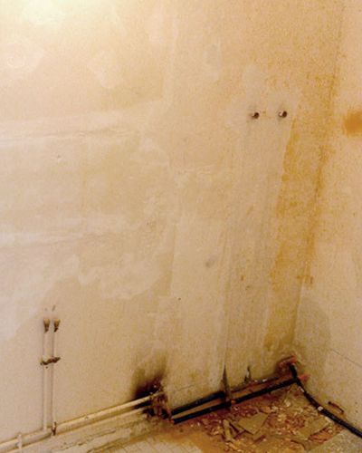 Mur de salle de bain décapé, traces d'humidité en pied de mur